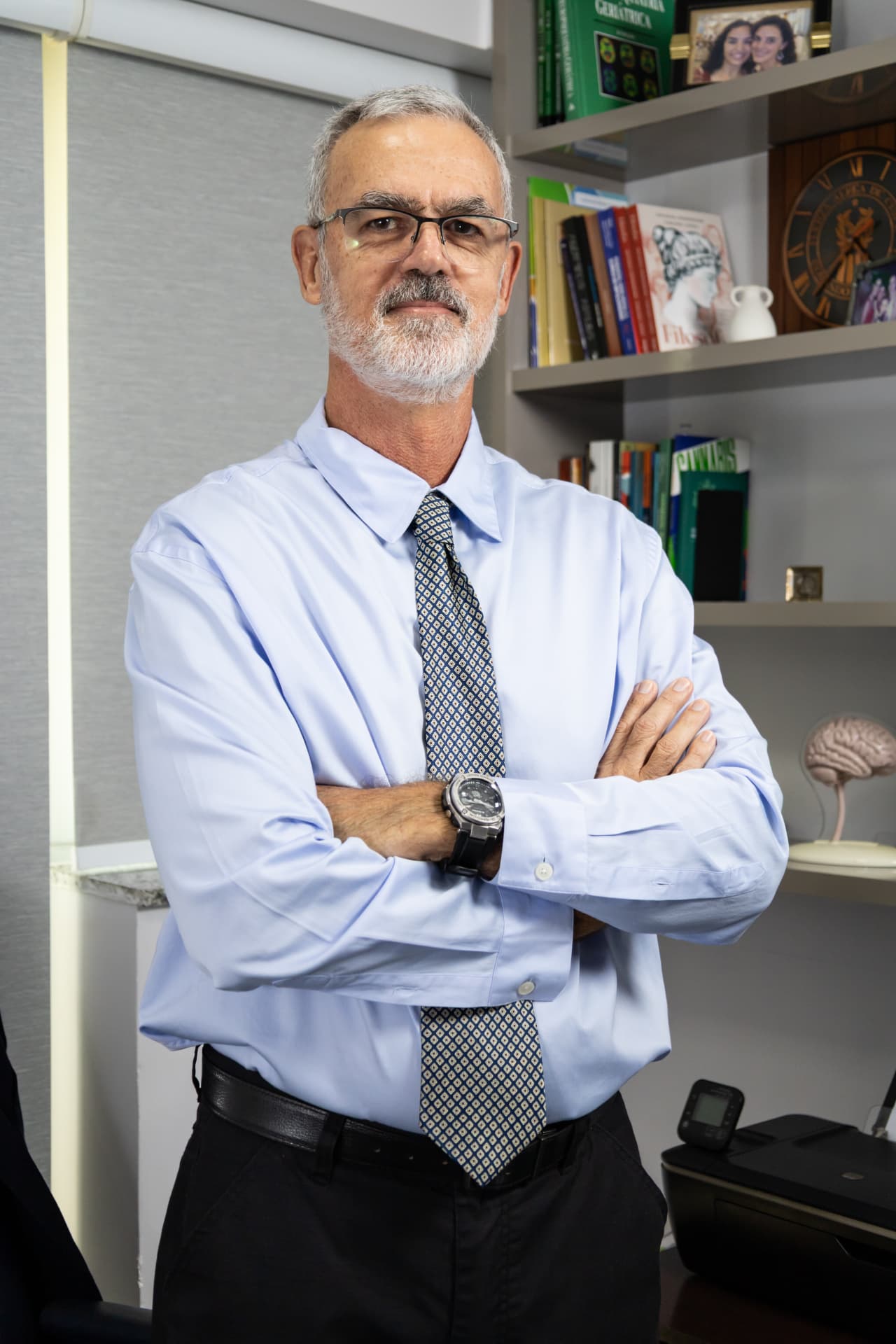 Dr. Francisco José Hennemann Neto, de braços cruzados, em seu consultório com estante de livros